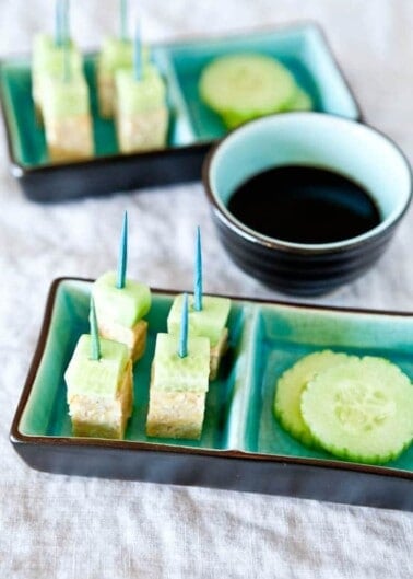 Cucumber and tofu bites with toothpick skewers served with soy sauce.