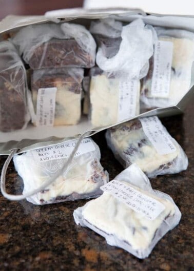 Various wrapped cheeses with handwritten labels on a countertop.
