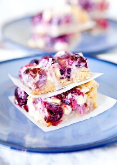 A stack of berry cheesecake bars on a blue plate.
