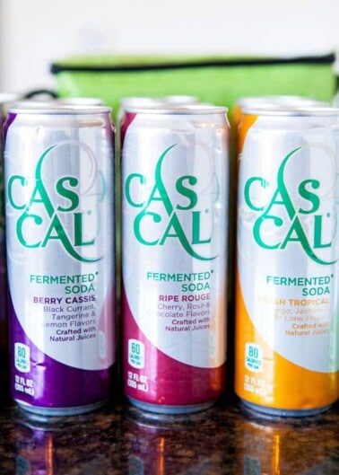 Three cans of cascal fermented soda in different flavors on a countertop.