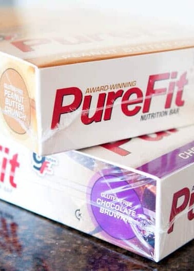 Stack of assorted purefit nutrition bars on a countertop.