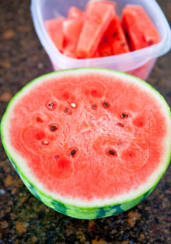 Watermelon half with slices in the background
