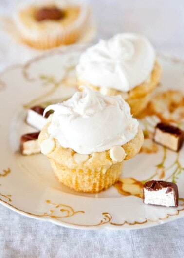 Mini cheesecakes topped with whipped cream on an ornate plate.