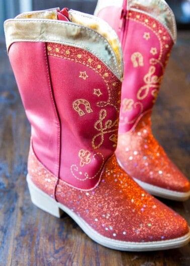 A pair of sparkly red cowboy boots with decorative stitching.