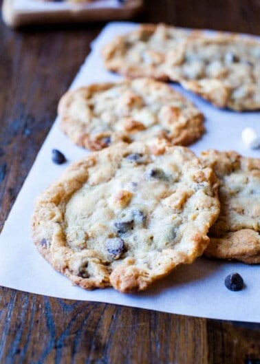 Freshly baked chocolate chip cookies on a paper surface.
