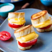 Grilled cheese sandwiches with tomato on a blue plate.