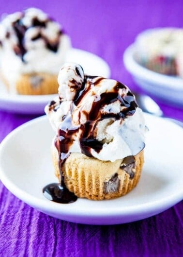 Vanilla ice cream with chocolate syrup on a muffin, served on a white plate with a purple background.