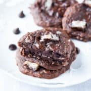 Chocolate cookies with white chunks on a white plate.