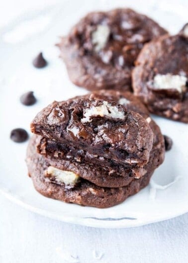 Chocolate cookies with white chunks on a white plate.