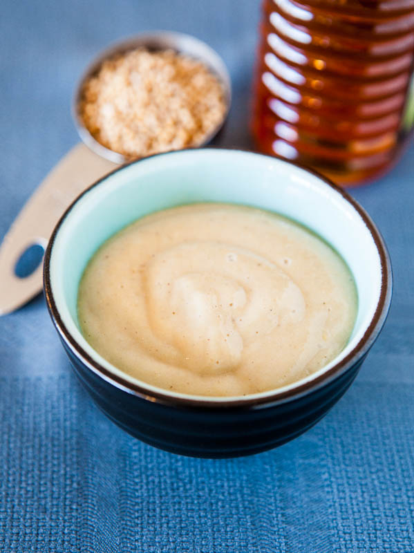 Honey mustard in bowl with honey and mustard seed in background