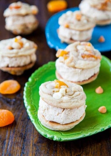 A stack of apricot frosted cookies on a green plate, with more cookies in the background.
