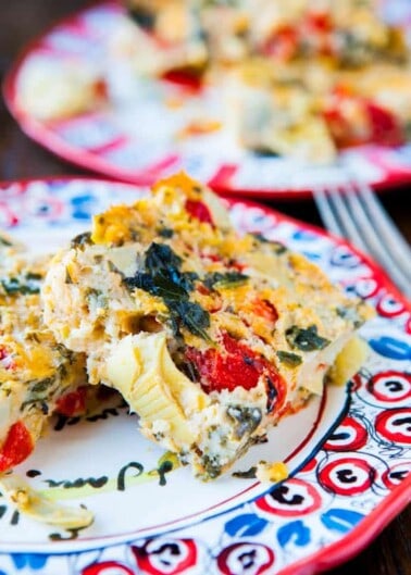A slice of vegetable frittata on a colorful plate.