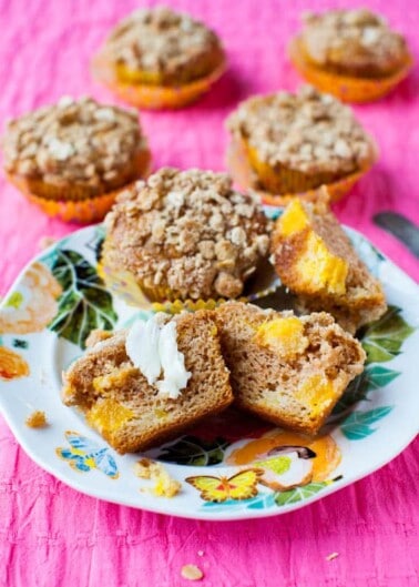 Freshly baked muffins on a colorful plate with one split open and buttered.
