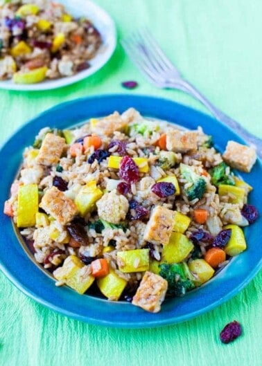 Stir-fried rice with tofu, vegetables, and cranberries served on a blue plate.