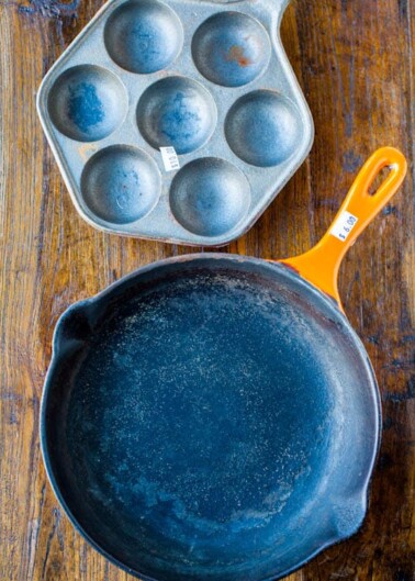 A cast iron skillet and a muffin pan on a wooden surface.
