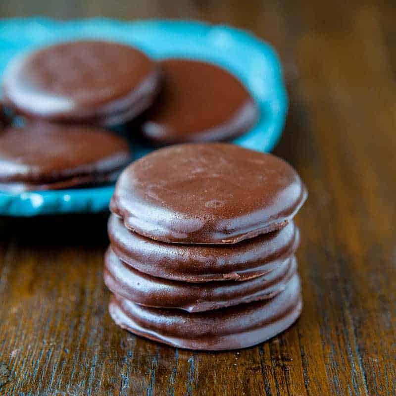 A stack of chocolate-covered cookies on a wooden surface.