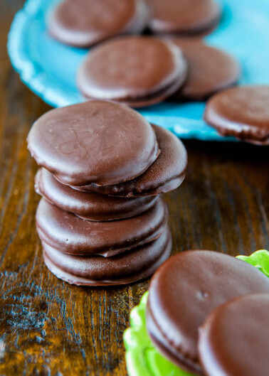 Stacks of chocolate-coated biscuits on a wooden table.