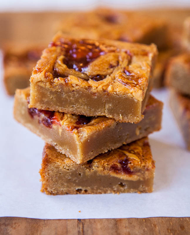 Three stacked Peanut Butter & Jelly Blondies on parchment paper