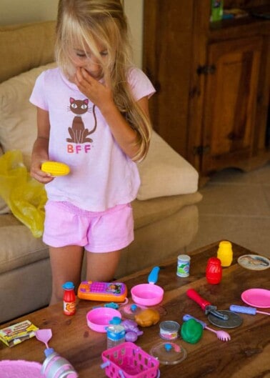 A young girl playing with a toy kitchen set indoors.