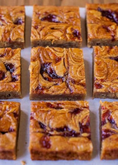 Homemade peanut butter and jelly bars arranged on a wooden surface.