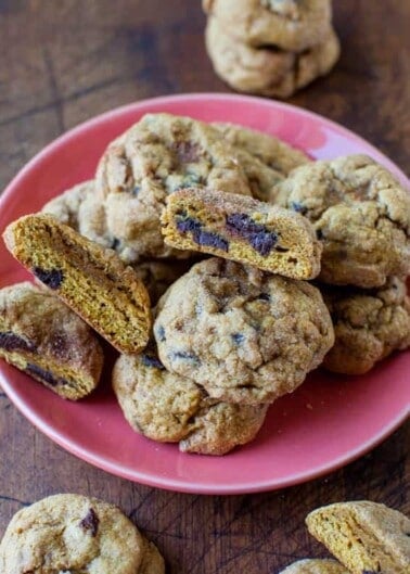 A plate of freshly baked cookies with some split open to reveal chocolate chips inside.