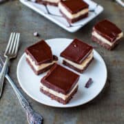 Chocolate-topped dessert bars on a plate with a vintage fork to the side.