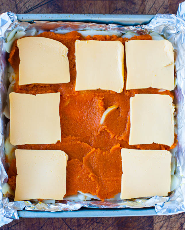 pumpkin puree in pan with cheese slices over it