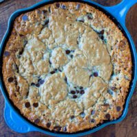 Freshly baked chocolate chip cookie in a blue cast-iron skillet.
