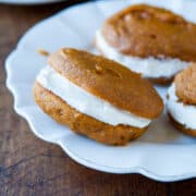 A pumpkin whoopie pie with cream filling on a white plate.
