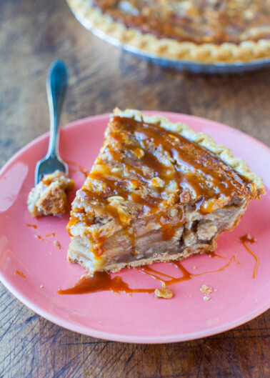 A slice of caramel-drizzled pie on a pink plate with a fork.