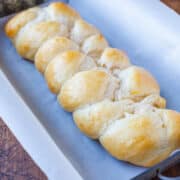 A freshly baked braided loaf of bread in a baking tray lined with parchment paper.