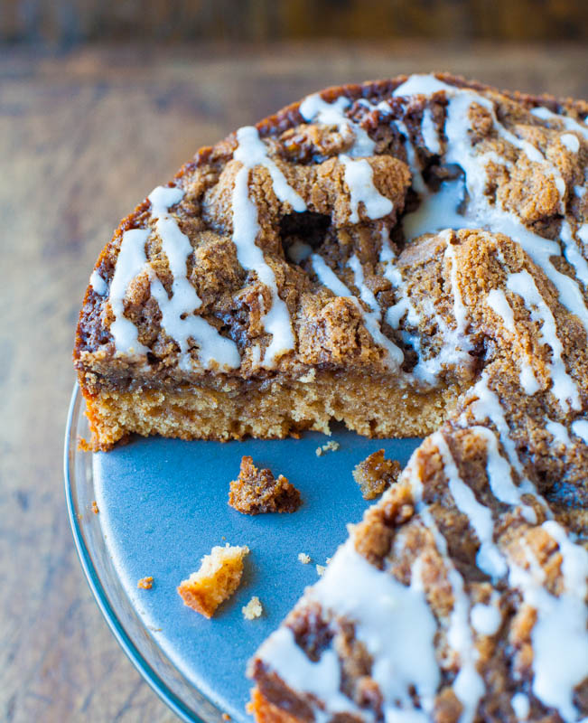 glazed cinnamon roll coffee cake on a cake stand with a slice missing 