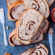 Sliced cinnamon swirl bread with a spreading knife and jam on the side.