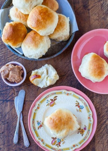A plate of freshly baked biscuits served with a side of butter on a wooden table.