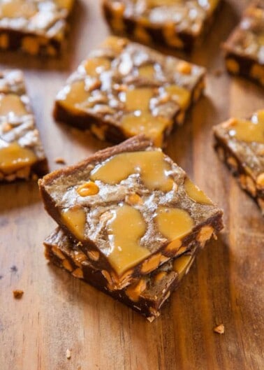 Chocolate caramel bars sprinkled with sea salt on a wooden surface.