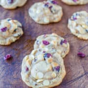A selection of white chocolate and cranberry cookies displayed on a wooden surface.