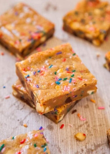 Stack of blondie bars with colorful sprinkles on a wooden surface.