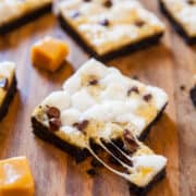 Toasted marshmallow and chocolate s'mores bars on a wooden surface.
