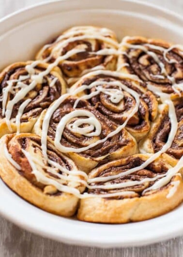 Freshly baked cinnamon rolls with icing in a baking dish.