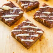 Triangular-shaped frosted brownies arranged on a wooden cutting board.