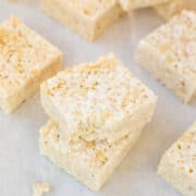 Homemade rice crispy treats stacked on parchment paper.