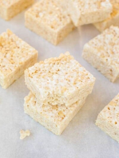 Homemade rice crispy treats stacked on parchment paper.
