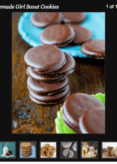 A stack of homemade chocolate-covered cookies on a wooden surface with more cookies on a blue plate in the background.