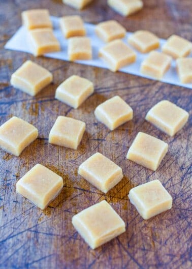 Homemade caramel squares on a wooden cutting board.