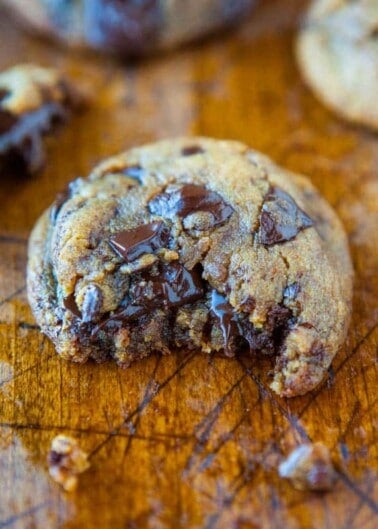 Freshly baked chocolate chip cookie on a wooden surface.