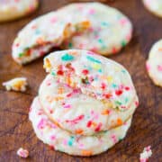 Sugar cookies with colorful sprinkles on a wooden surface.