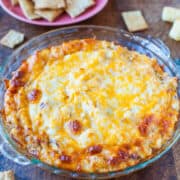 Baked cheesy dip served in a glass dish with crackers on the side.