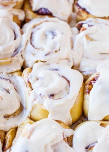 Freshly baked cinnamon rolls topped with white icing.