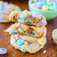 Stack of cookies with colorful candy pieces on a wooden surface.