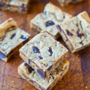 Chocolate chip cookie bars stacked on a wooden surface.